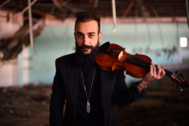 Akram Abdulfattah - Photo by Basel Hajoij. Akram holding a fiddle on his left shoulder.