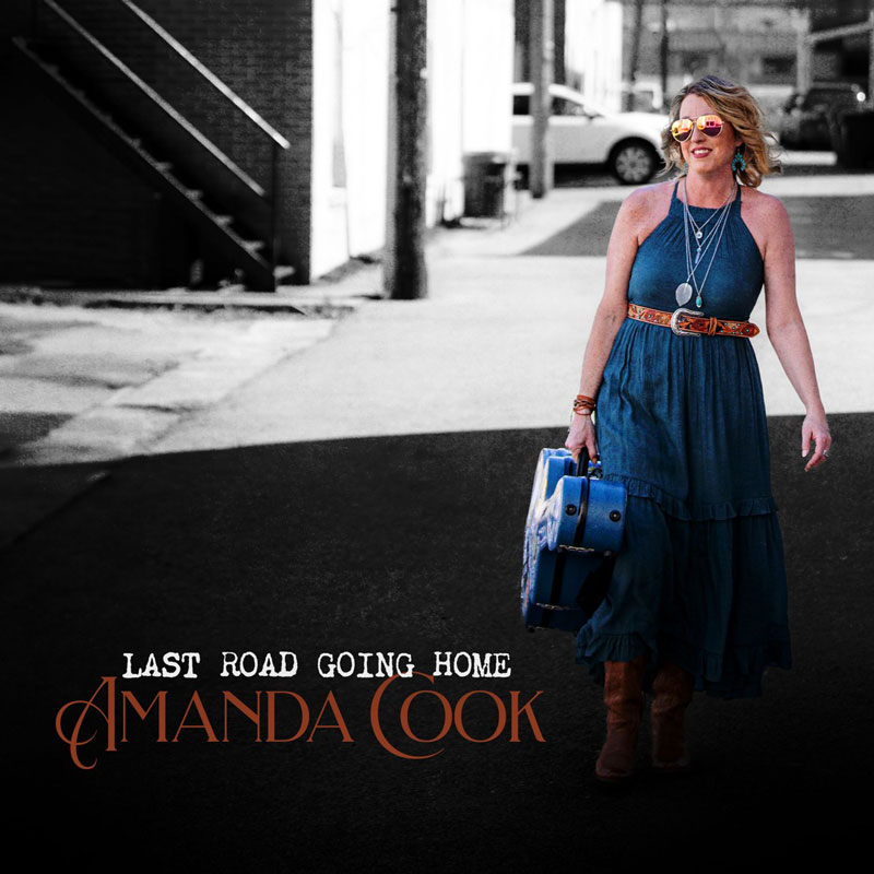 Amanda Cook - Last Road Going Home cover artwork. It shows the aryist outdoors, walking, in a blue dress, carrying a guitar case.