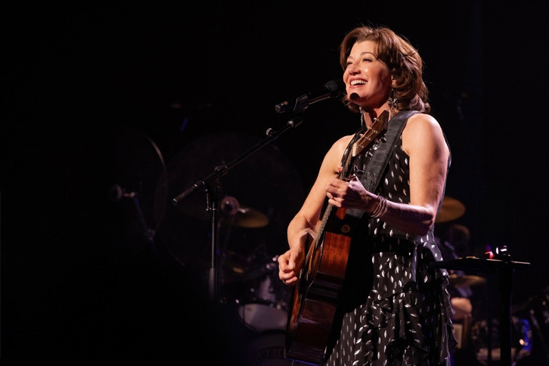Amy Grant playing live holding a guitar.