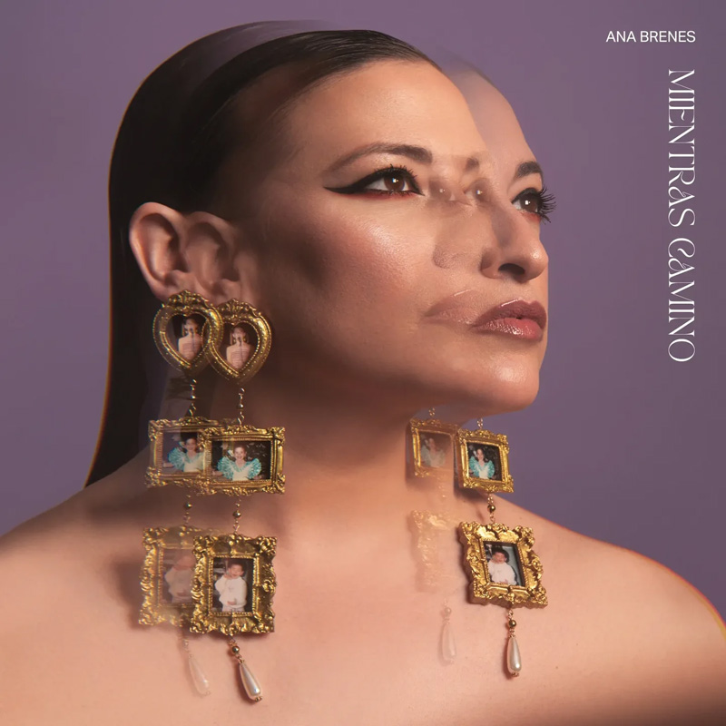 Ana Brenes - Mientras camino cover artwork. A portrait of Ana against a lavender background, shown with a double-exposure effect. She wears gold earrings adorned with tiny framed family photographs and pearl drops.