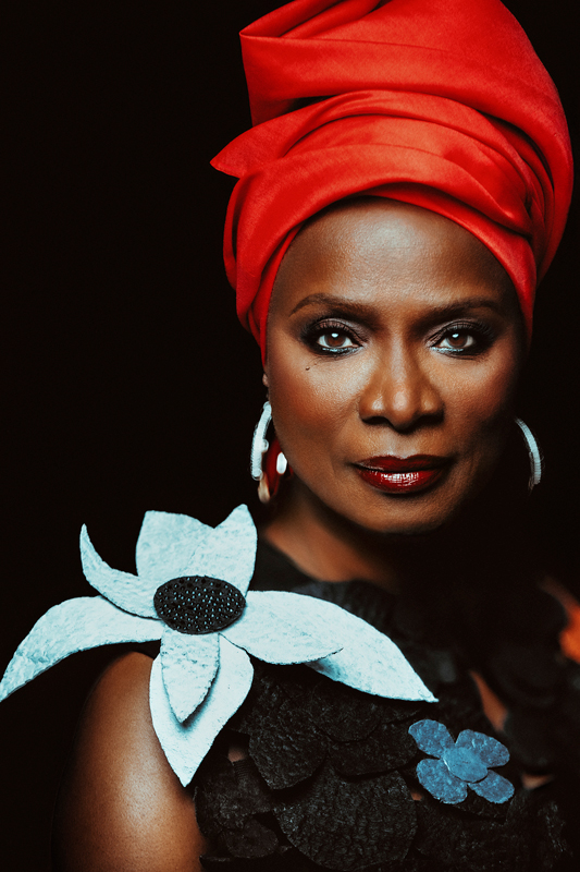 Angélique Kidjo - Photo by Brantley Gutiérrez. Angélique wearing a turban and a dress with a large flower on the shoulder.