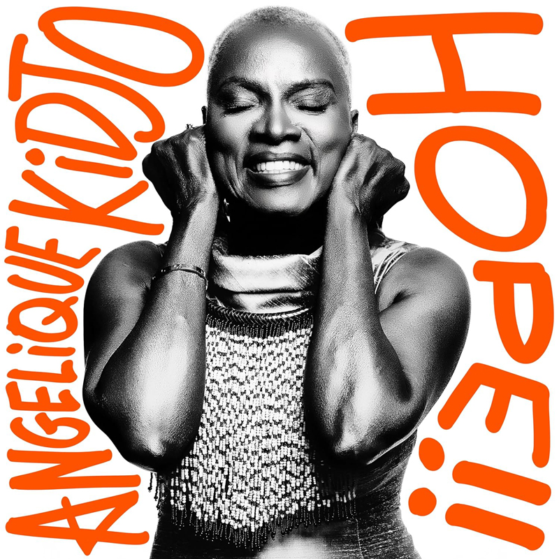 Angelique Kidjo - Hope!! covr artwork. Black and white photo of Angelique smiling with her fists on her ears.