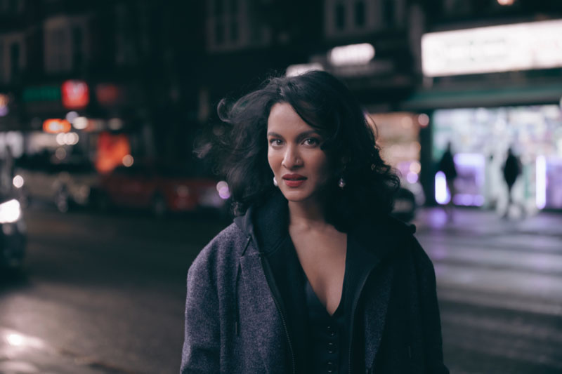 Anoushka Shankar standing in a street at night.