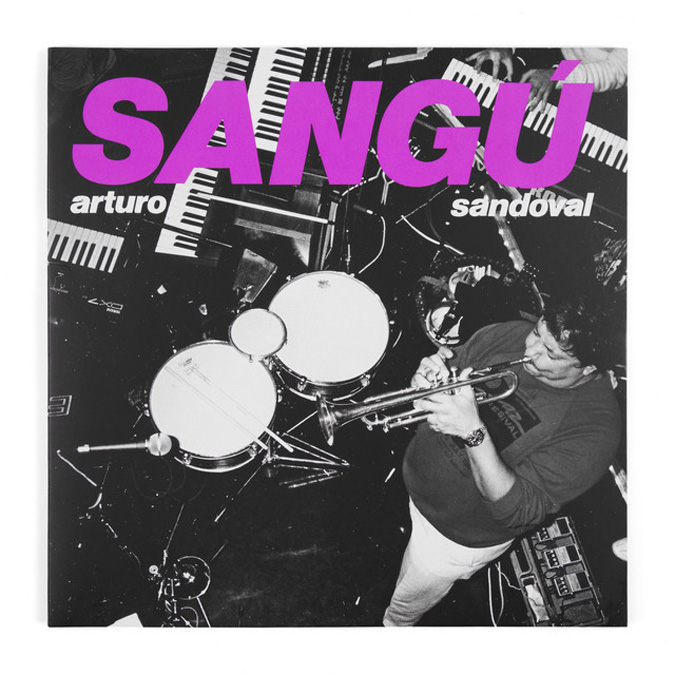 Arturo Sandoval - Sangú. A black and white photo of Aturo playing trumpet in the studio.