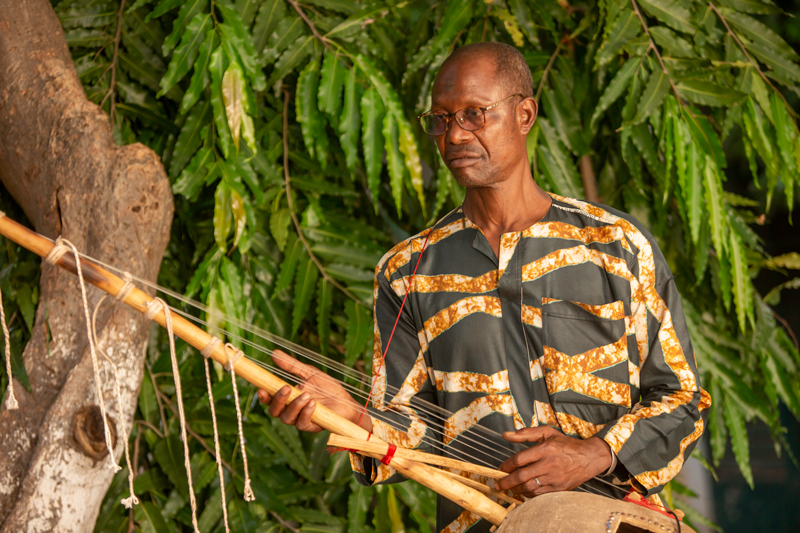 Benego Diakité - Photo by Aboubacar Traoré. Benego playing kamale ngoni outdoors.