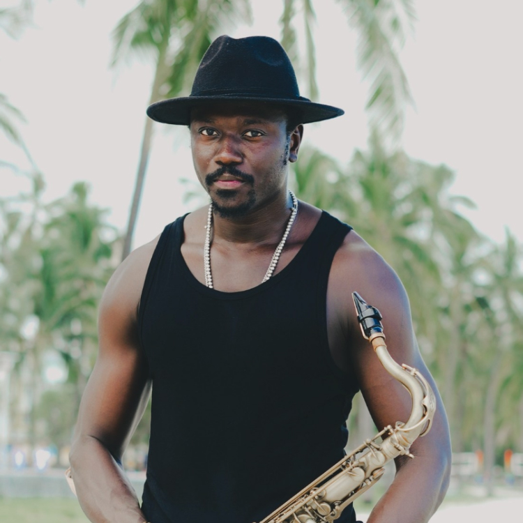 Cheikh Ibra Fam wearing a black hat, holding a saxophone.