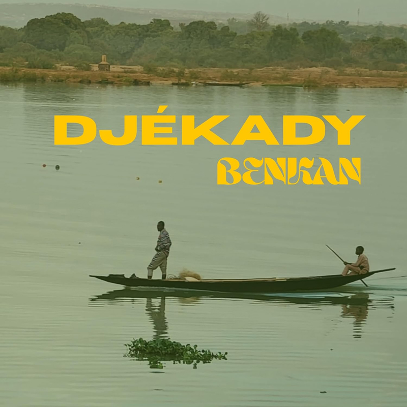 A riverside scene fills the cover, where two people travel in a long wooden canoe across still greenish water. Soft reflections ripple beneath them, and a tree-lined shore stretches in the distance. Yellow lettering announces Djékady above and Benkan below.