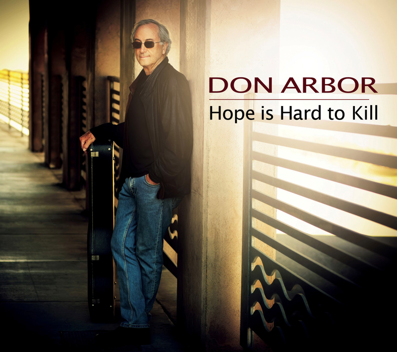 Don Arbor - Hope is Hard To Kill covr artwork. Don standing by a wall, holding his guitar.