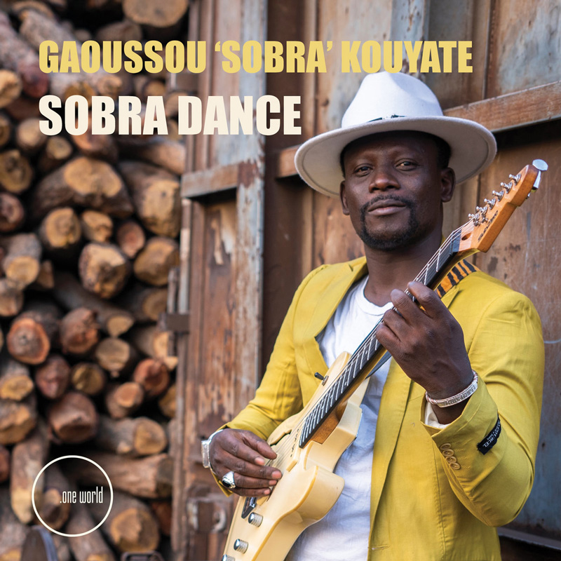 Gaoussou ‘Sobra’ Kouyate - Sobra Dance cover artwork. Gaoussou wearing ayellow jacket and whoite hat, holding an electric guitar.