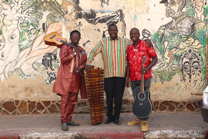 Guitari Baro standing by a wall holding their musical instruments - Photo by Carolina Vallejo