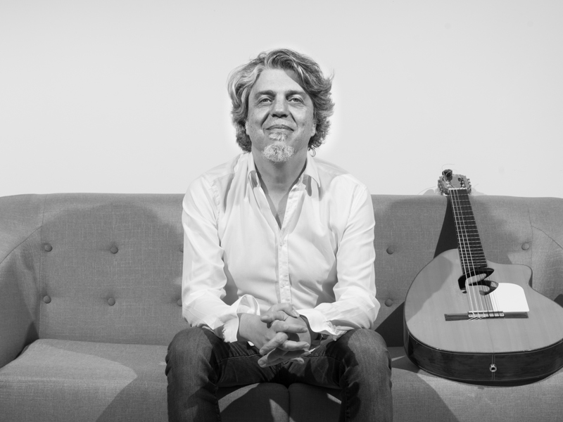 Josete Ordóñez sitting on a sofa, next to a guitar.