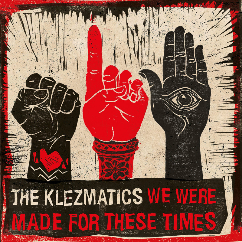 A protest-style illustration shows three raised hands against a beige background: a black clenched fist on the left, a red hand in the center pointing upward, and a black open palm on the right with an eye symbol. Along the bottom, blocky lettering reads We Were Made For These Times by The Klezmatics.
