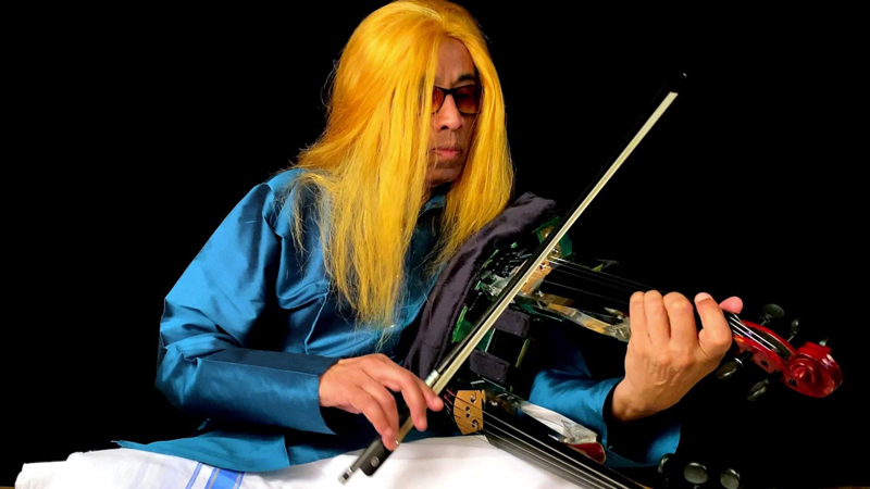 L. Shankar playing his double violin, with his long hair dyed yellow.