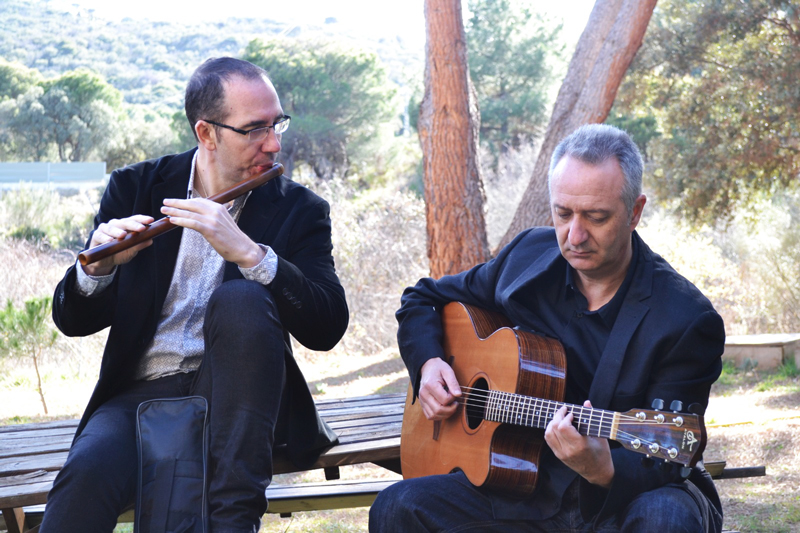 La Musgaña members playing guitar and flute by some woods