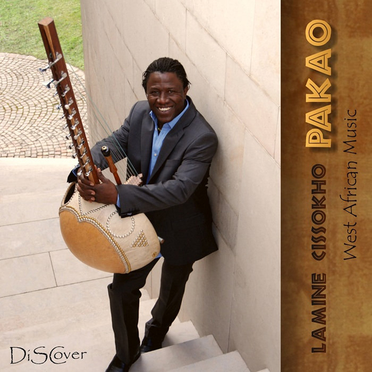 Lamine Cissokho Pakao cover artwork. A color photo of Lamine in a suit, leaning against a wall, playing kora.