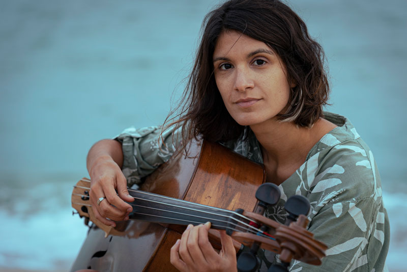 Lucrecia Carrizo - Photo by Koky Schroeder. a photo of the artist holding the cello guitar-style.