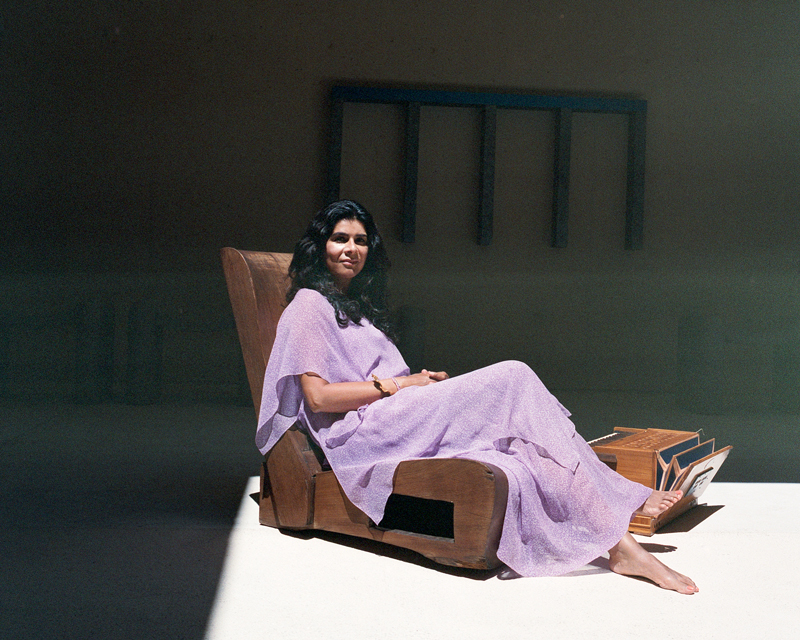 Manizeh - Photo by Florian Schneider. Manizeh resting on a lounge chair, wearing a violet dress.
