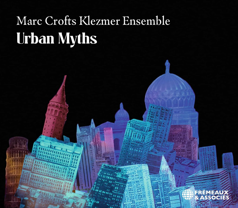 The album cover for Urban Myths by Marc Crofts Klezmer Ensemble features a cityscape composed of colorful, overlapping architectural landmarks from around the world. The buildings, tinted in vibrant blues, purples, and reds, appear stacked at odd angles, suggesting an urban collage. The title is prominently displayed in a bold serif font, with the ensemble's name above it. The Frémeaux & Associés logo appears in the lower right corner.