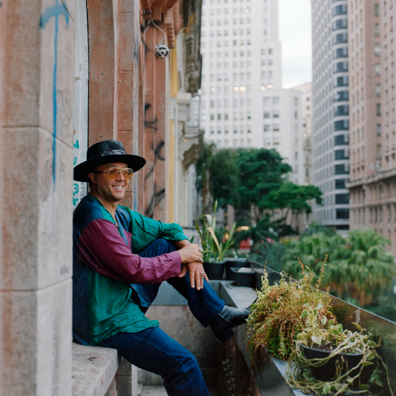 Moyses Dos Dantos — Photo by Brian Cross. Moyses leaning against a building wall wearing a black hat.