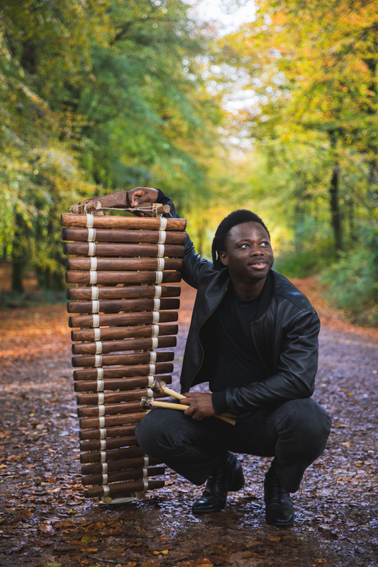 Nfamady Kouyate - Photo by Nadine Ballantyne. Nfamady holding a balafon vertically.