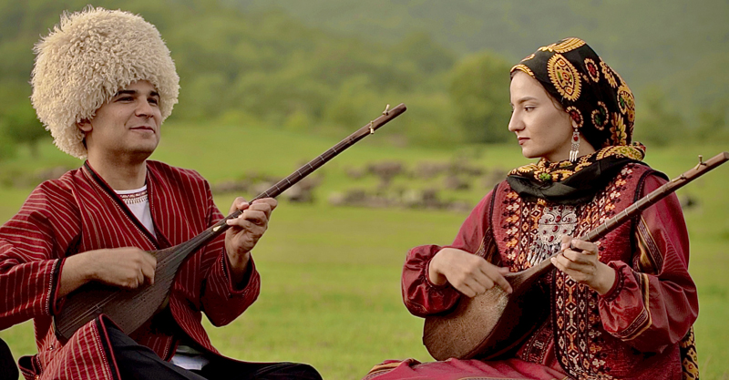 Oghlan Bakhshi & Zyyada Jumayeva playing their musical instruments outdoors.