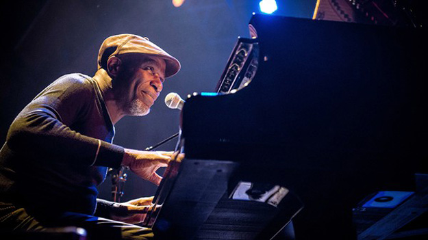 Ray Lema. Photo by Olivier Hoffschir. Ray playing piano wearing a cap.