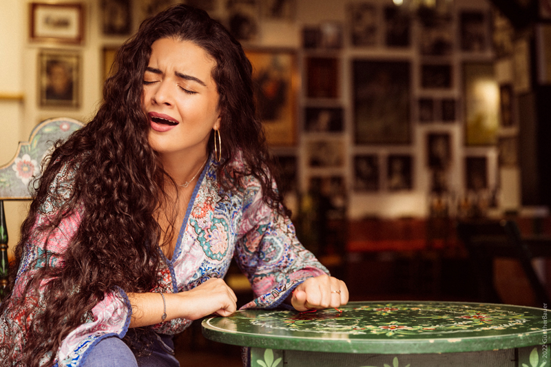 Reyes Carrasco singing at a table in a café or club.