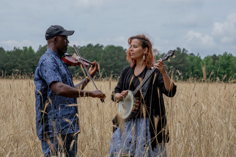 Rhiannon Giddens & Justin Robinson playing banjo outdoors. Photo Credit Karen Cox