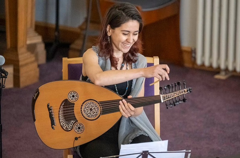 Rihab Azar sitting, holding an oud.