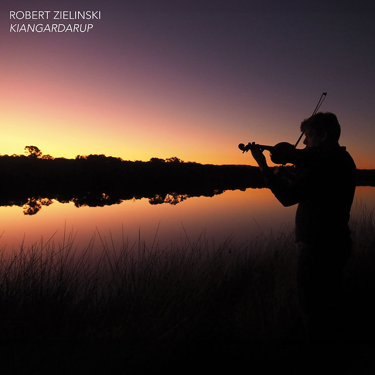 The album cover for Robert Zielinski's Kiangardarup features a serene silhouette of the artist playing the violin at sunset. The scene is set against a colorful sky transitioning from orange to purple, reflected in a still body of water below. The foreground is framed by gentle grasses,