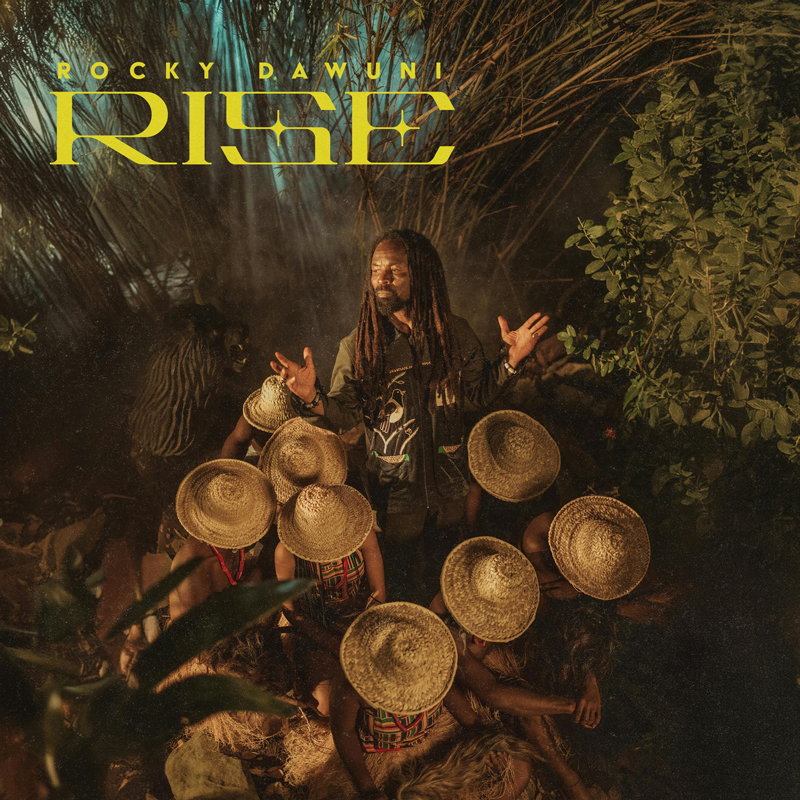 Rocky Dawuni - Rise artwork. The artist surrounded by people wearing tradiional straw hats.