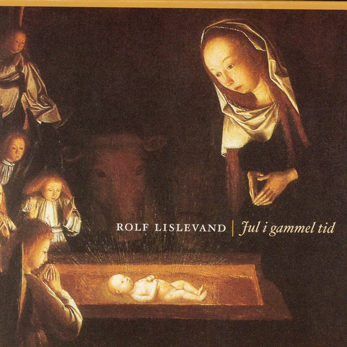 A warm, candlelit nativity scene fills the cover of Jul i gammel tid, with softly illuminated figures gathered around the newborn child.