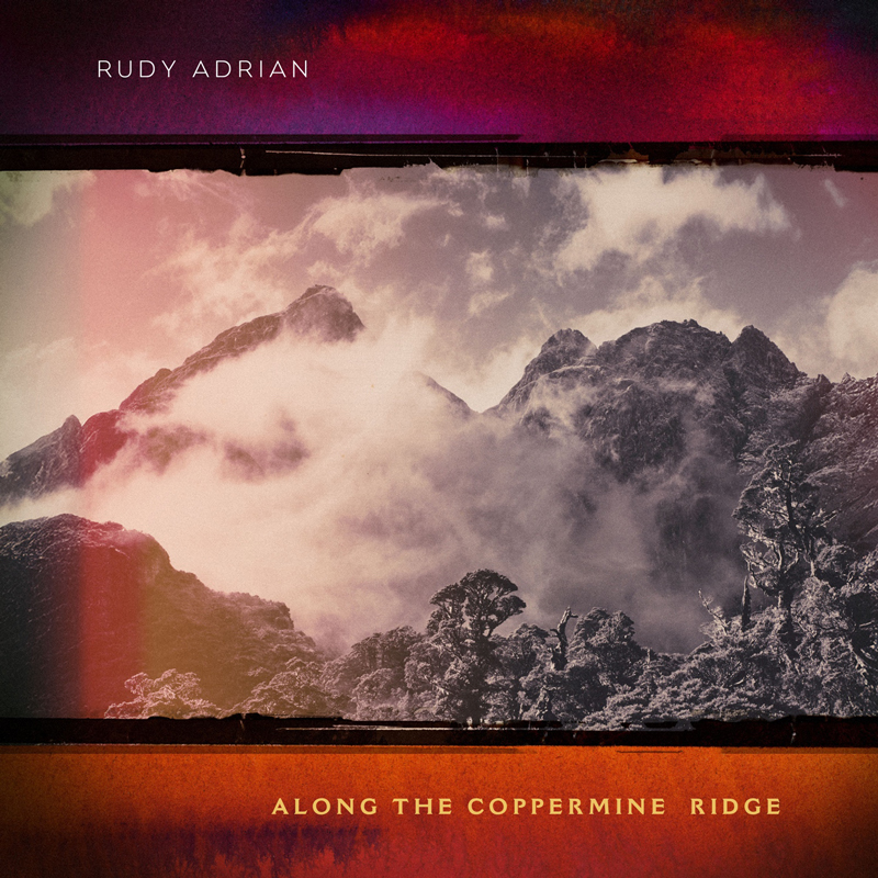 Jagged mountain peaks wrapped in mist beneath a muted sky. Red and amber light edge the image, contrasting with grays and purples in the terrain. The artist name sits at the top, while the album title, Along The Coppermine Ridge, is at the bottom.