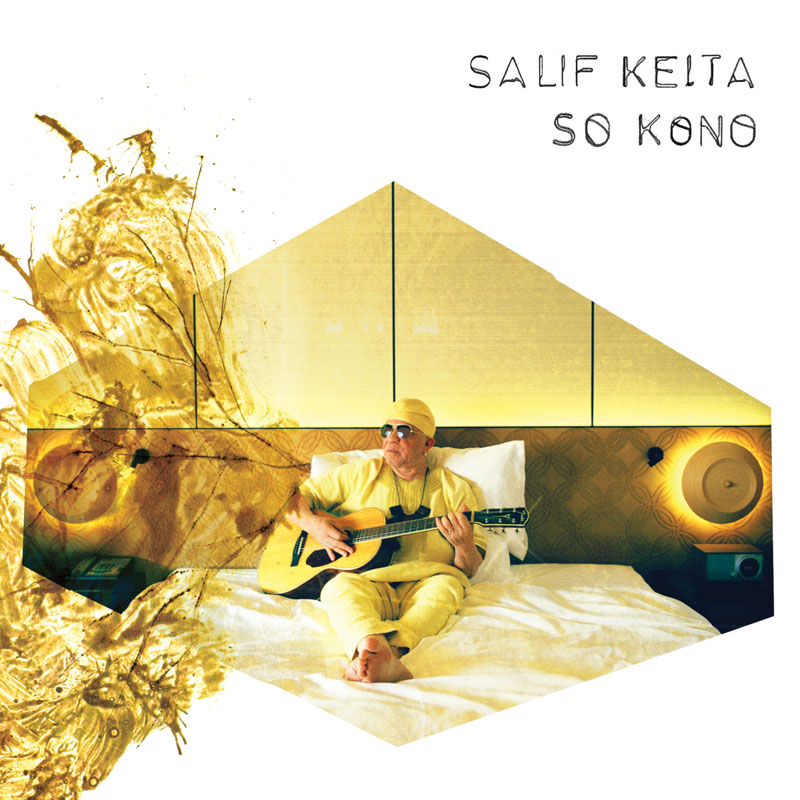 The album cover for So Kono by Salif Keita features the legendary Malian musician sitting barefoot on a white bed, dressed in a monochromatic yellow outfit with sunglasses and a matching headwrap. He holds an acoustic guitar. The background is a warmly lit, modern bedroom with geometric panels forming a house-like structure. A dynamic splash of gold paint extends from the left side. handwritten and minimal.