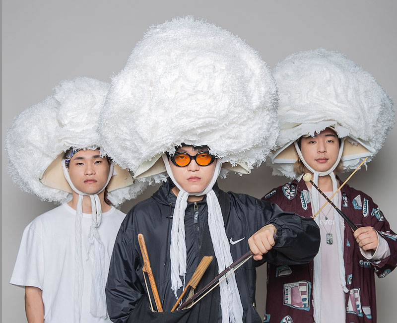 Sangjaru - Photo Credit Seungryul Na. The three band members wearing very large white wigs, like enormous white afros.