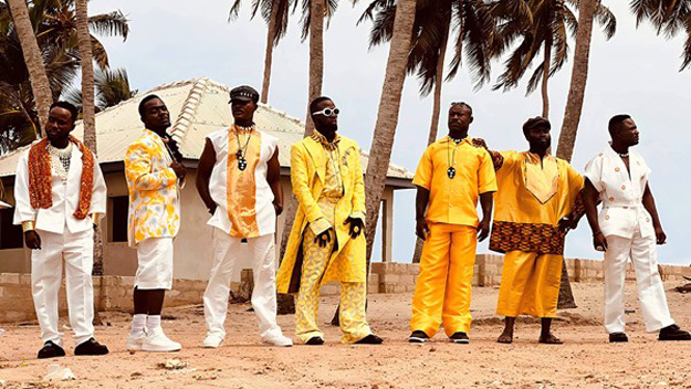 Santrofi standing by palm trees, wearing traditional clothes.