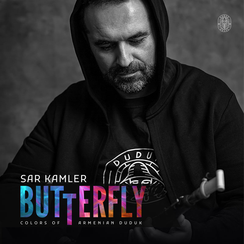 Sar Kamler - Butterfly: Colors of Armenian Duduk cover artwork. A black and white photo of the artist. He has a beard, wears a hoodie and is holding a duduk.