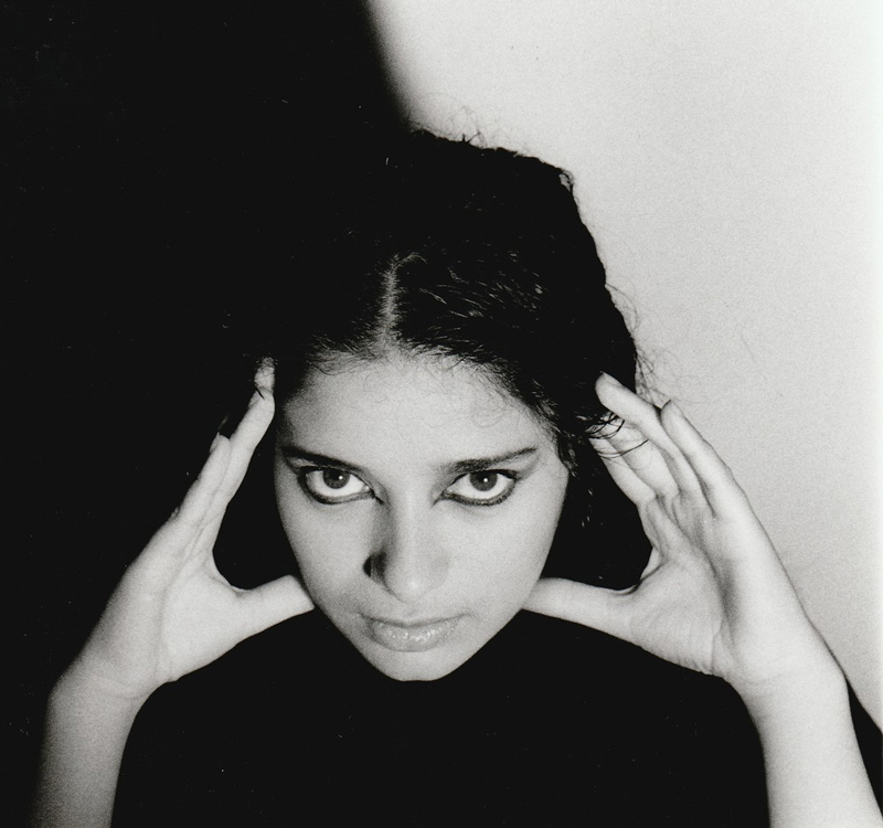 Black and white photo of Sheila Chandra with hands holding her head.