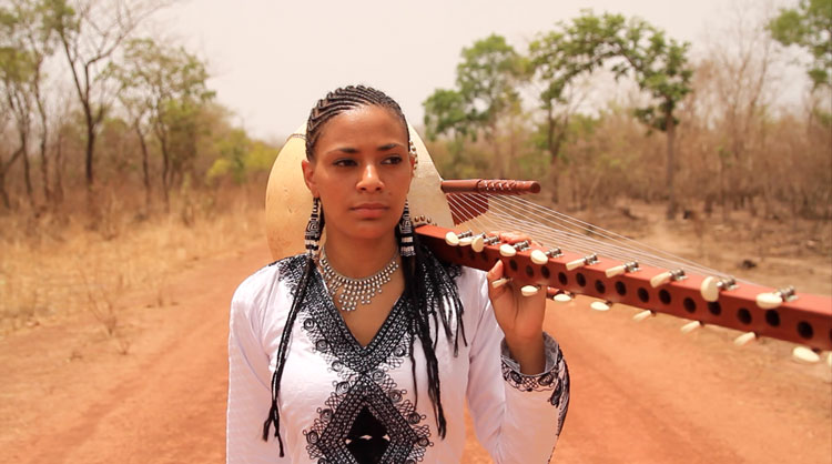 Sona Jobarteh walking with a kora