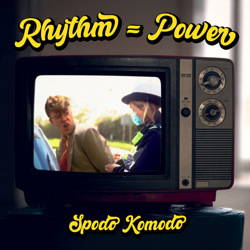 Spodo Komodo -Rhythm = Power cover artwork. A TV set slowing an image of a man arrested by a female police officer.