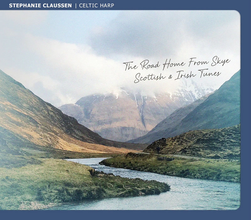 The album cover for The Road Home From Skye: Scottish & Irish Tunes by Stephanie Claussen features a landscape photograph of a Highland valley. A winding river cuts through the green and brown terrain, leading the eye toward towering mountains partially shrouded in mist.