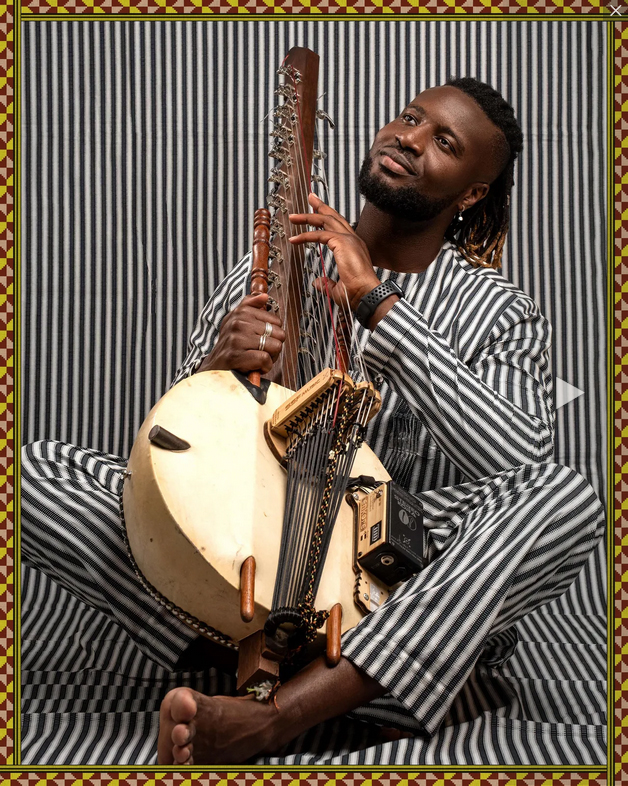 Suntou Susso indoor shot holding a kora.