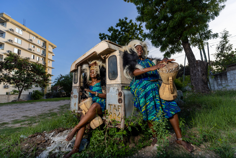 The Zawose Queens - Photo by Michael Mbwambo. The two artists holding drums by a Land Rover.