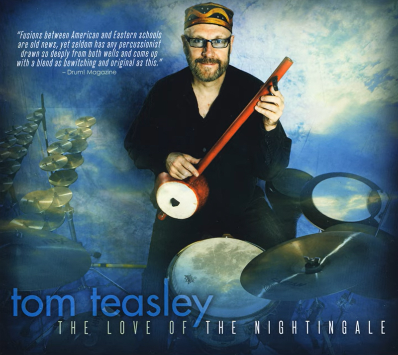 Tom Teasley Dance of Aphrodite cover artwork. Tom playing an eastern lute surrounded by percussion instruments.