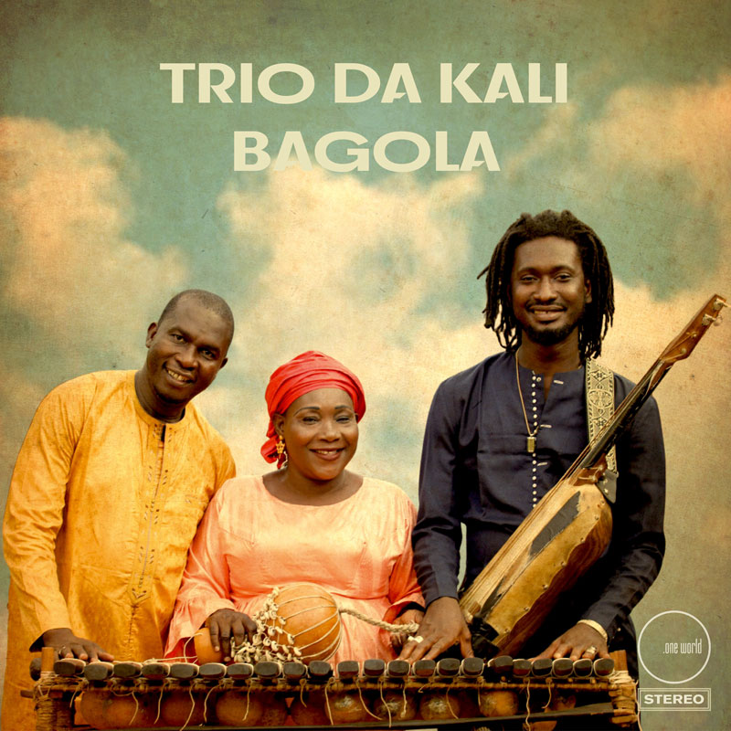 Trio Da Kali - Bagola cover artwork. A color photo of the trio outdoors with clouds in the background.