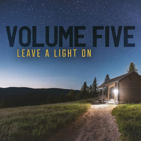 The album cover for Leave a Light On by Volume Five depicts a warmly lit cabin on a grassy hillside under a star-filled night sky.