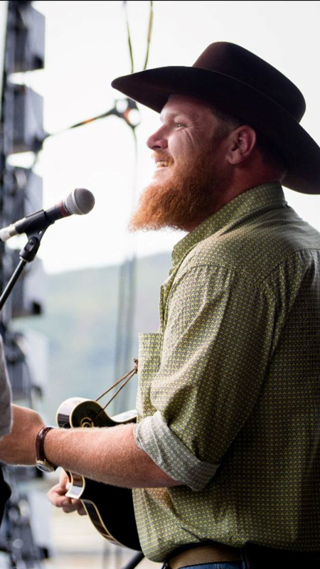 Will Clark wearing a cowboy hat, playing mandolin