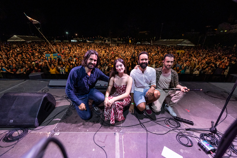 Xara on stage facing the camera with a large audience behind them.
