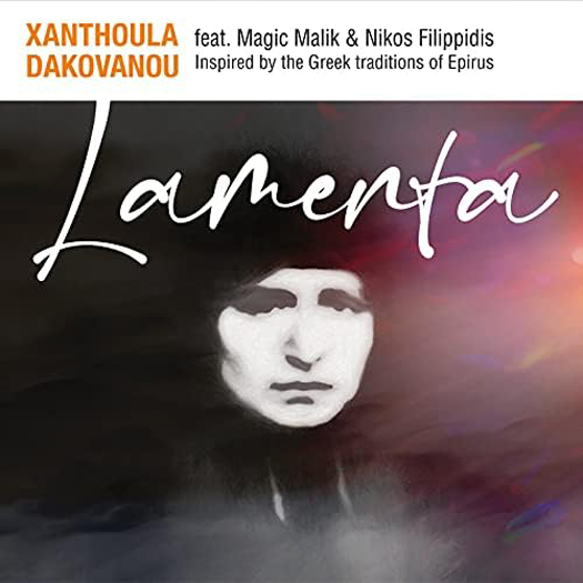 The album cover for Lamenta by Xanthoula Dakovanou features a solemn face, pale, expressionless, and framed by dark shadows. The title Lamenta is handwritten in flowing white script across the center. At the top, bold orange and black text credits Dakovanou alongside featured artists Magic Malik and Nikos Filippidis.