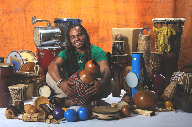 Dendê Macedo surrounded by percussion instruments